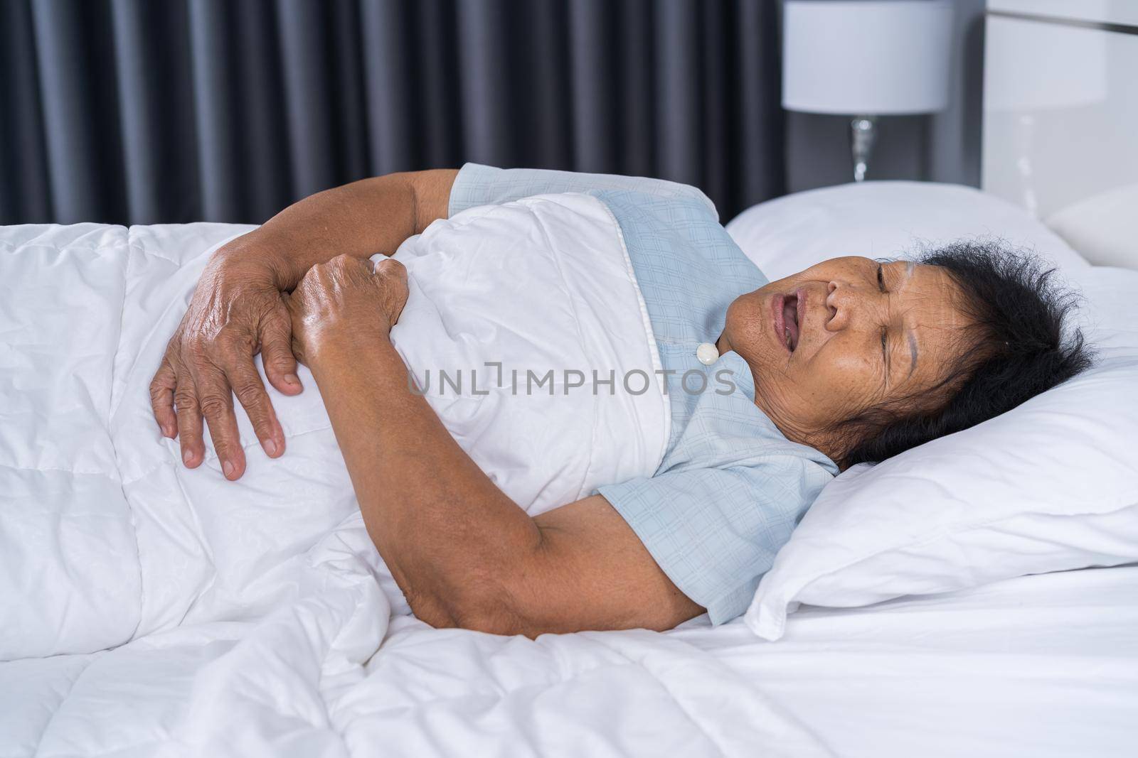 senior woman suffering from stomachache on bed  by geargodz