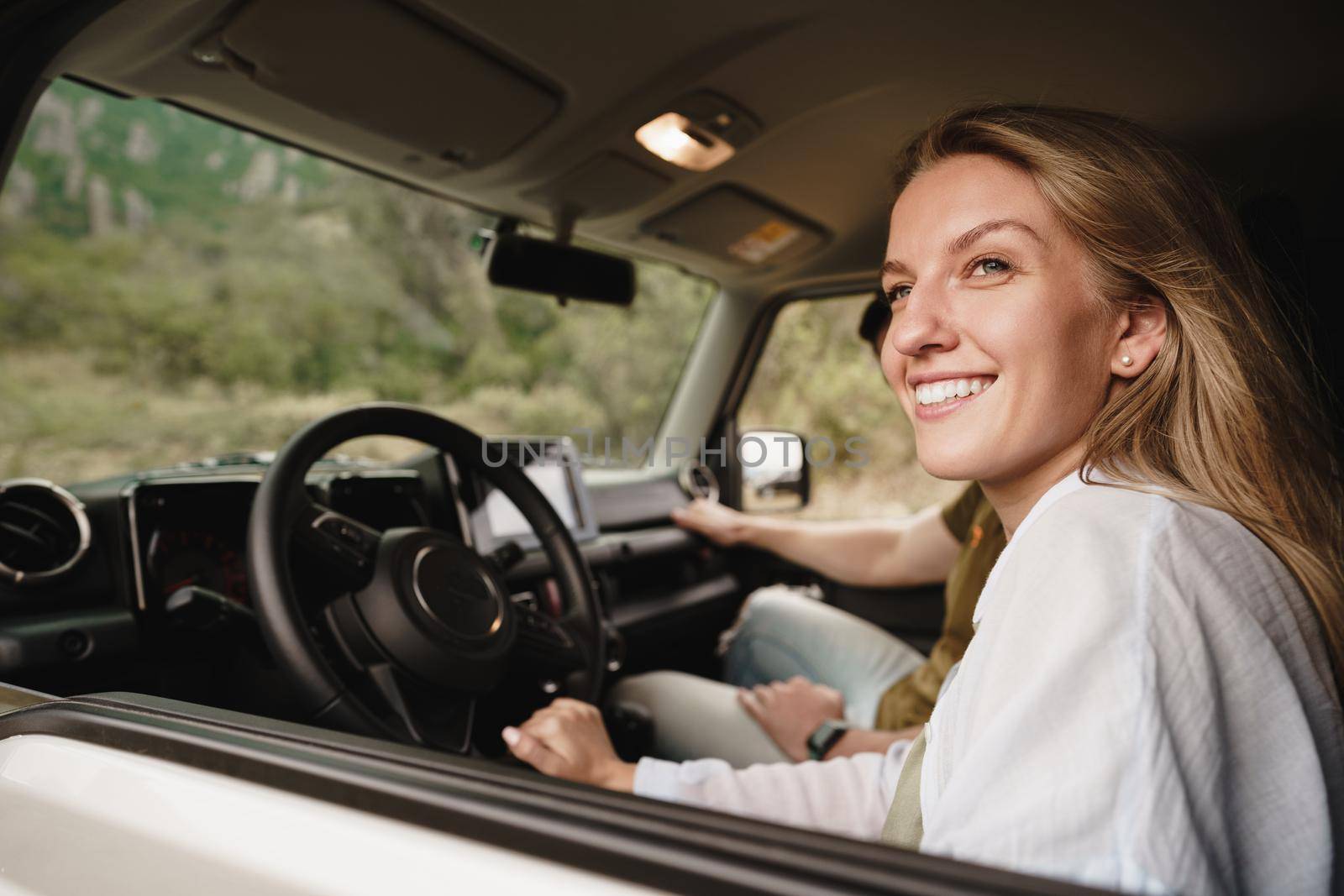 Beautiful young smiling couple sitting on front passenger seats and driving a car