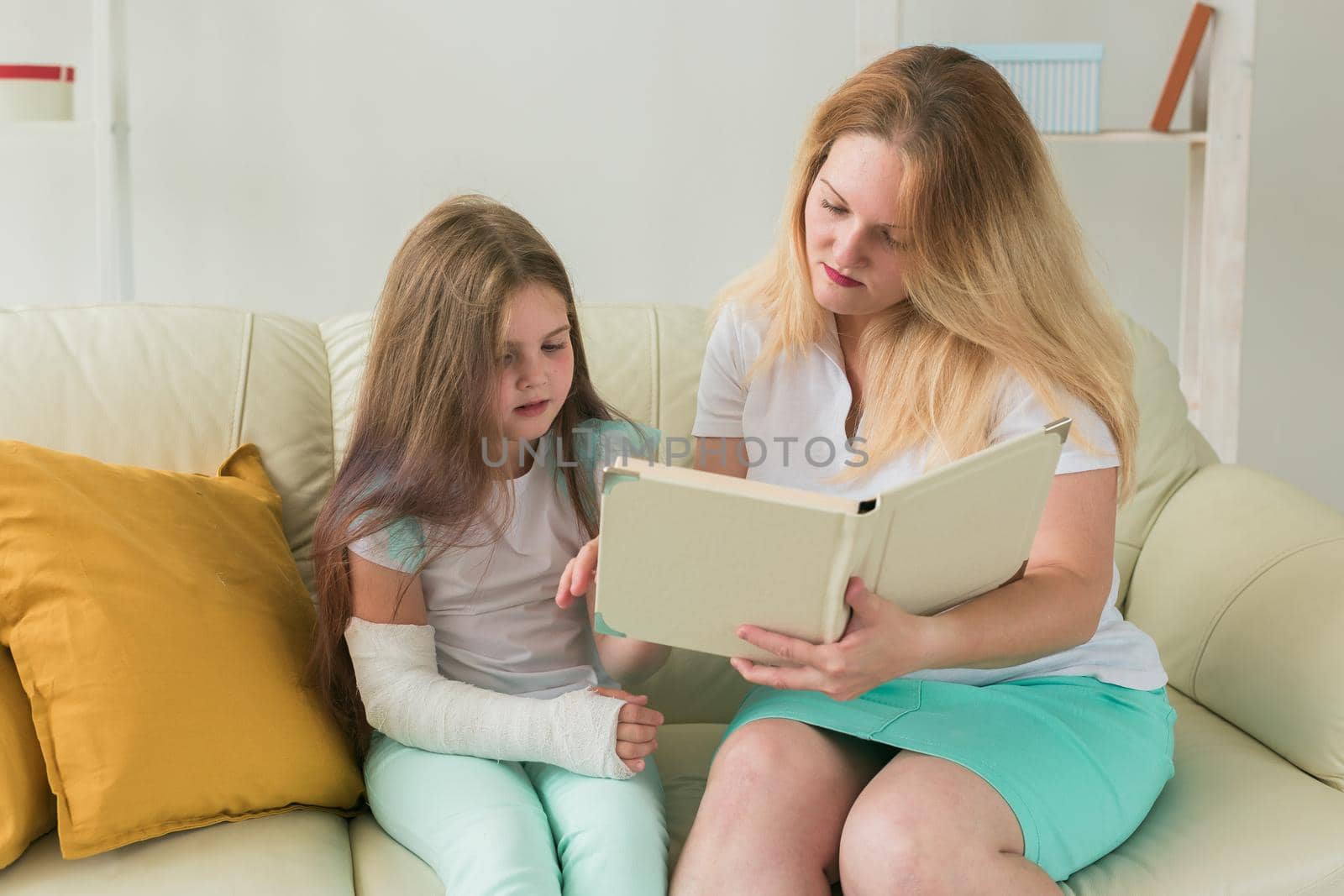 Child with broken arm and gypsum spend time at home with mother. Childhood illnesses, a positive outlook and recovery