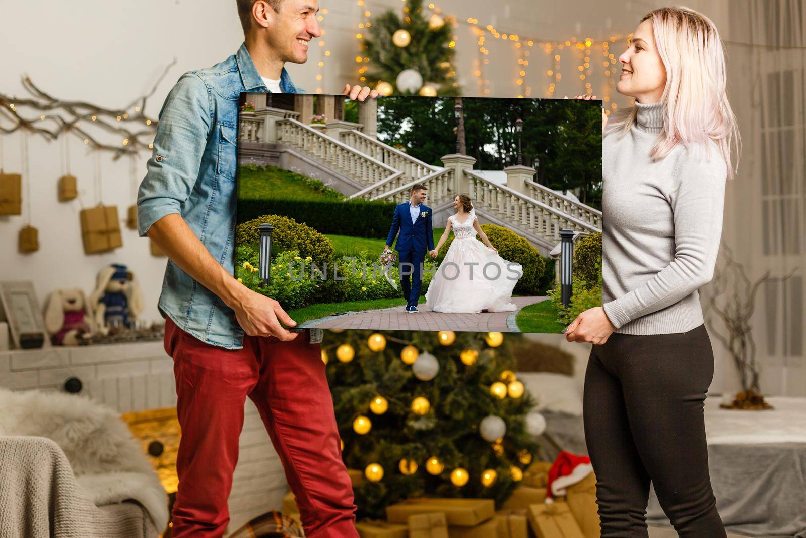 woman holding a photo canvas on the background of a Christmas interior.