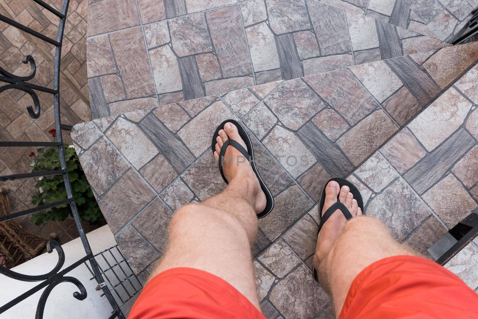 Men's legs in black flip flops and red shorts go down and walk down the stairs. Walking style by AYDO8