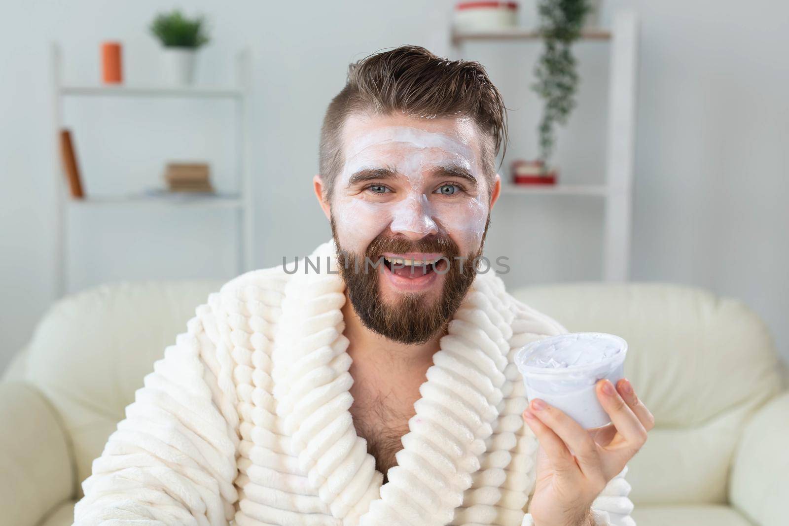 Bearded guy applying anti-wrinkle cream on his face. Skin care and spa for man concept