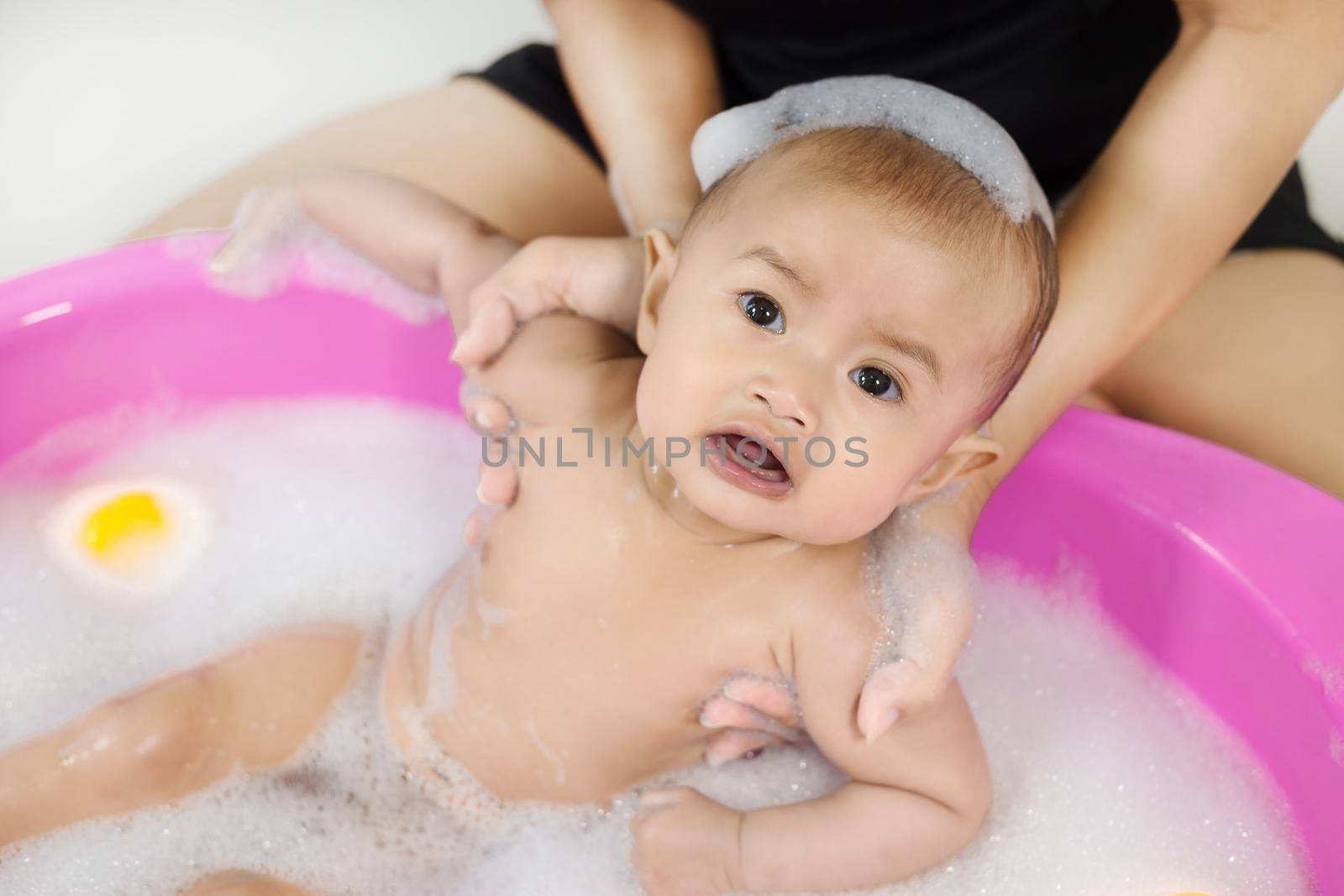 baby taking a bath in bathtub and playing with foam bubbles by geargodz