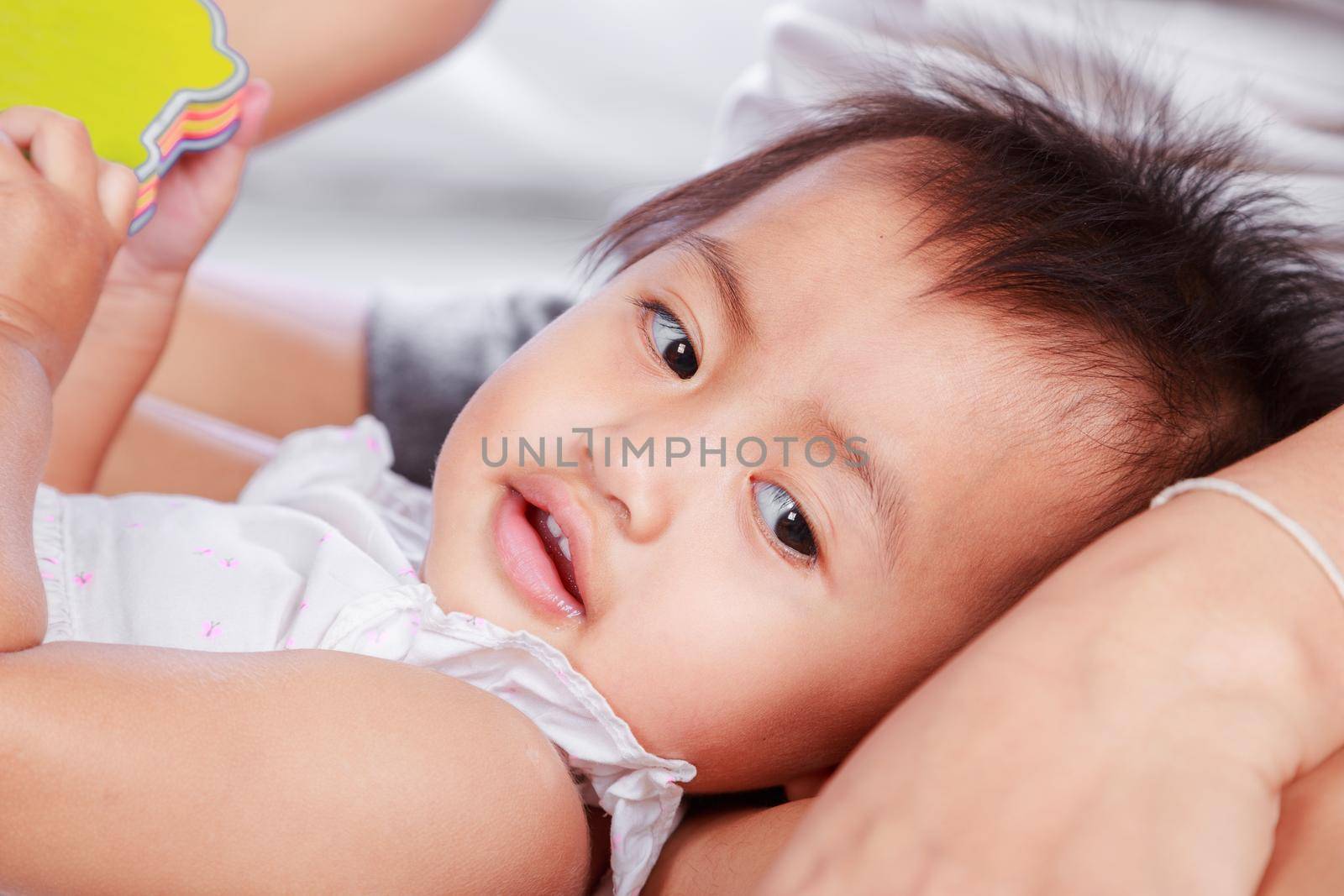 asian baby lying on mother's knees