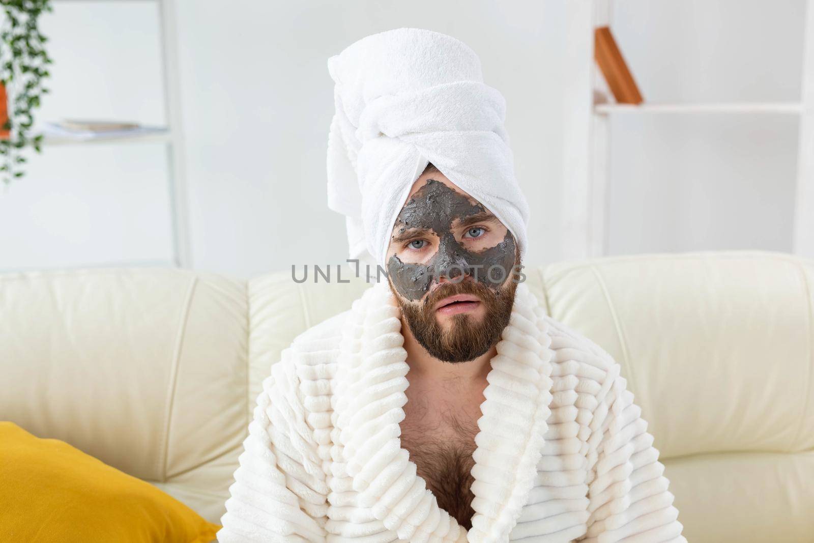 Bearded man has clean fresh skin, wears beauty clay mask on face and enjoys beauty treatments. Spa at home, body and skin care.