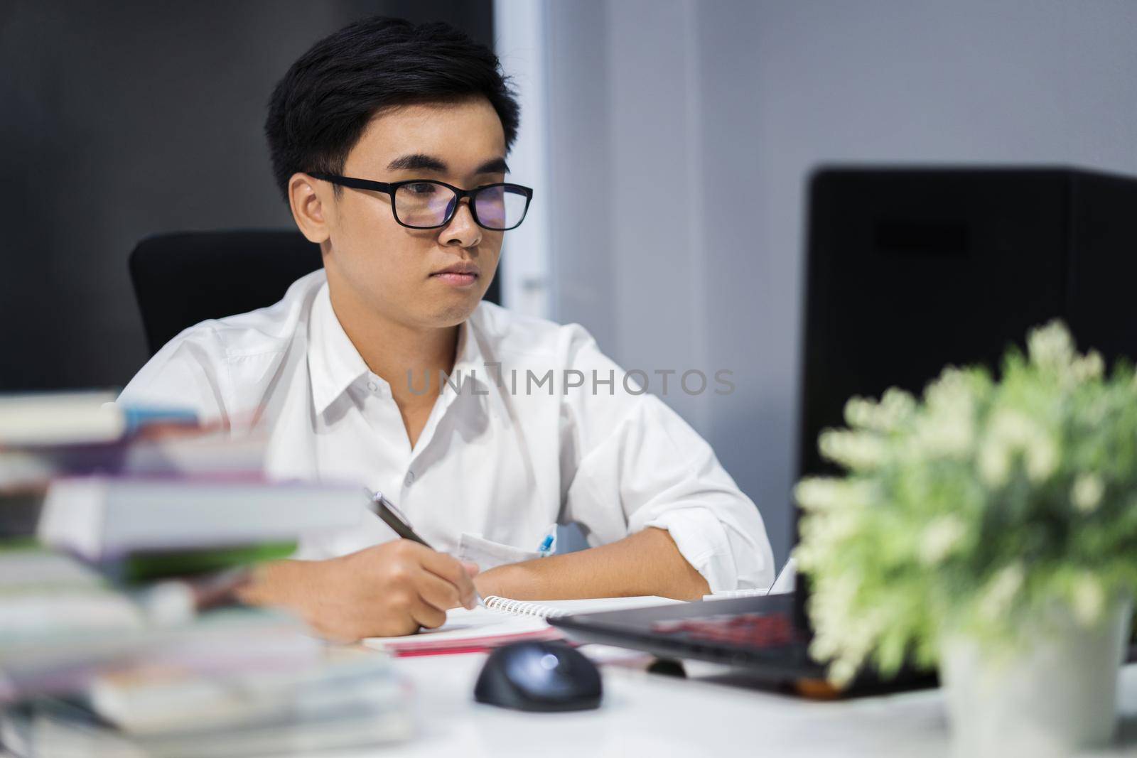 young man studying and writing on notebook with laptop  by geargodz