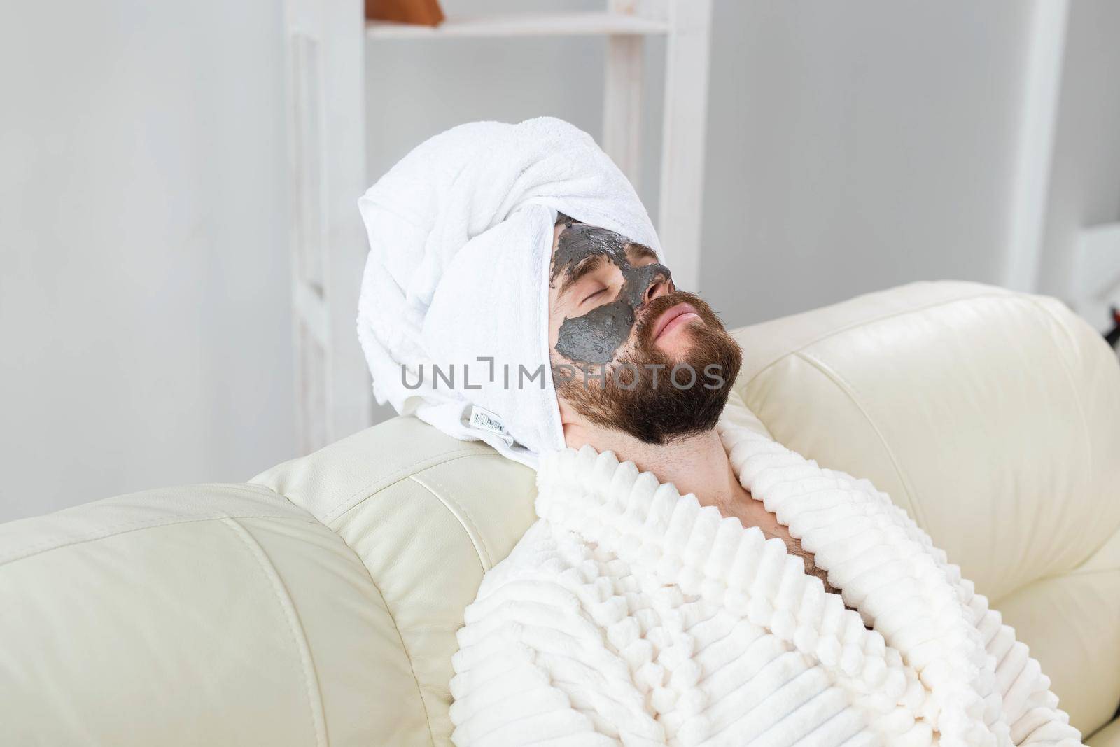 Bearded man has clean fresh skin, wears beauty clay mask on face and enjoys beauty treatments. Spa at home, body and skin care.