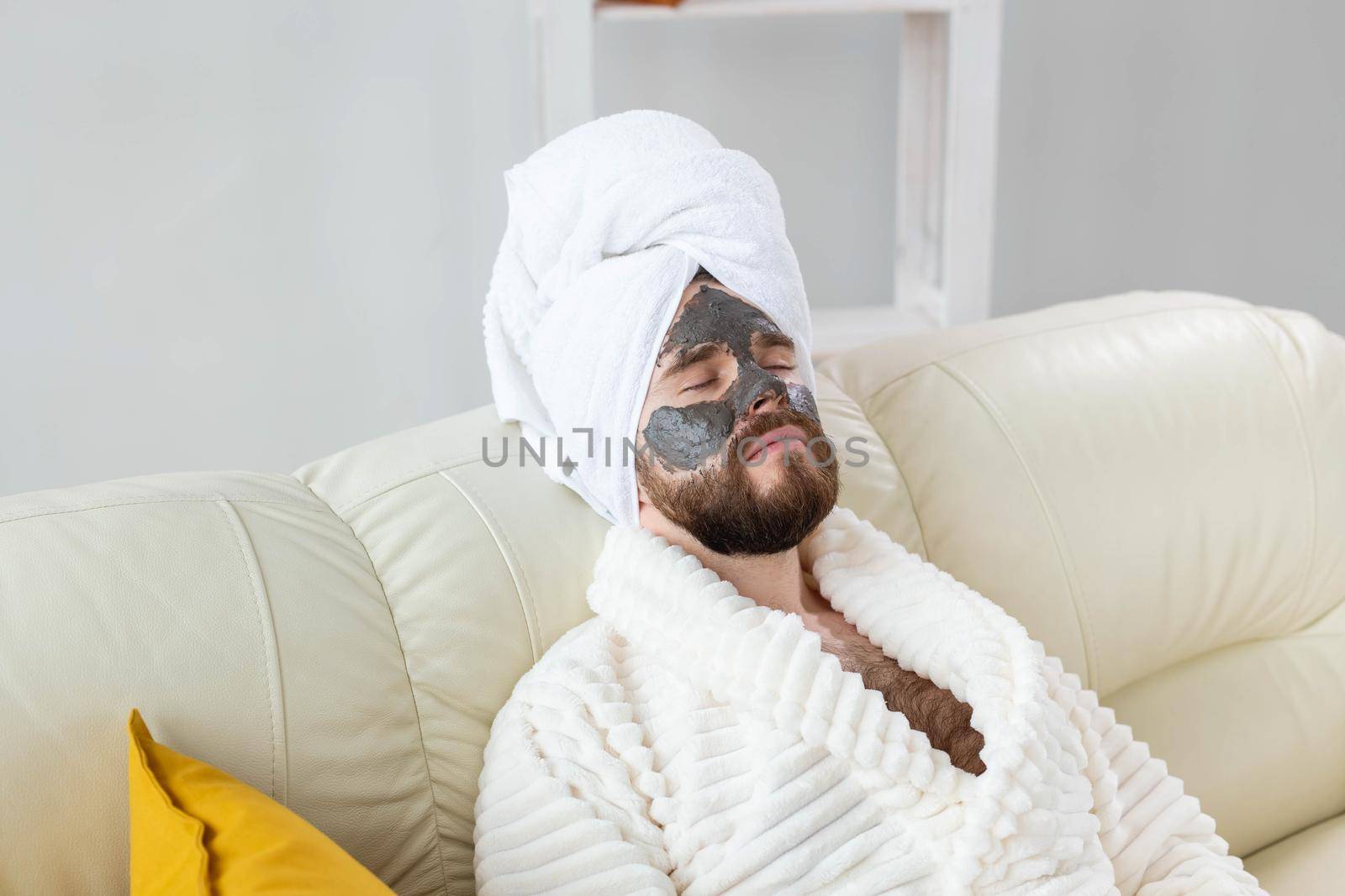 Bearded man has clean fresh skin, wears beauty clay mask on face and enjoys beauty treatments. Spa at home, body and skin care.