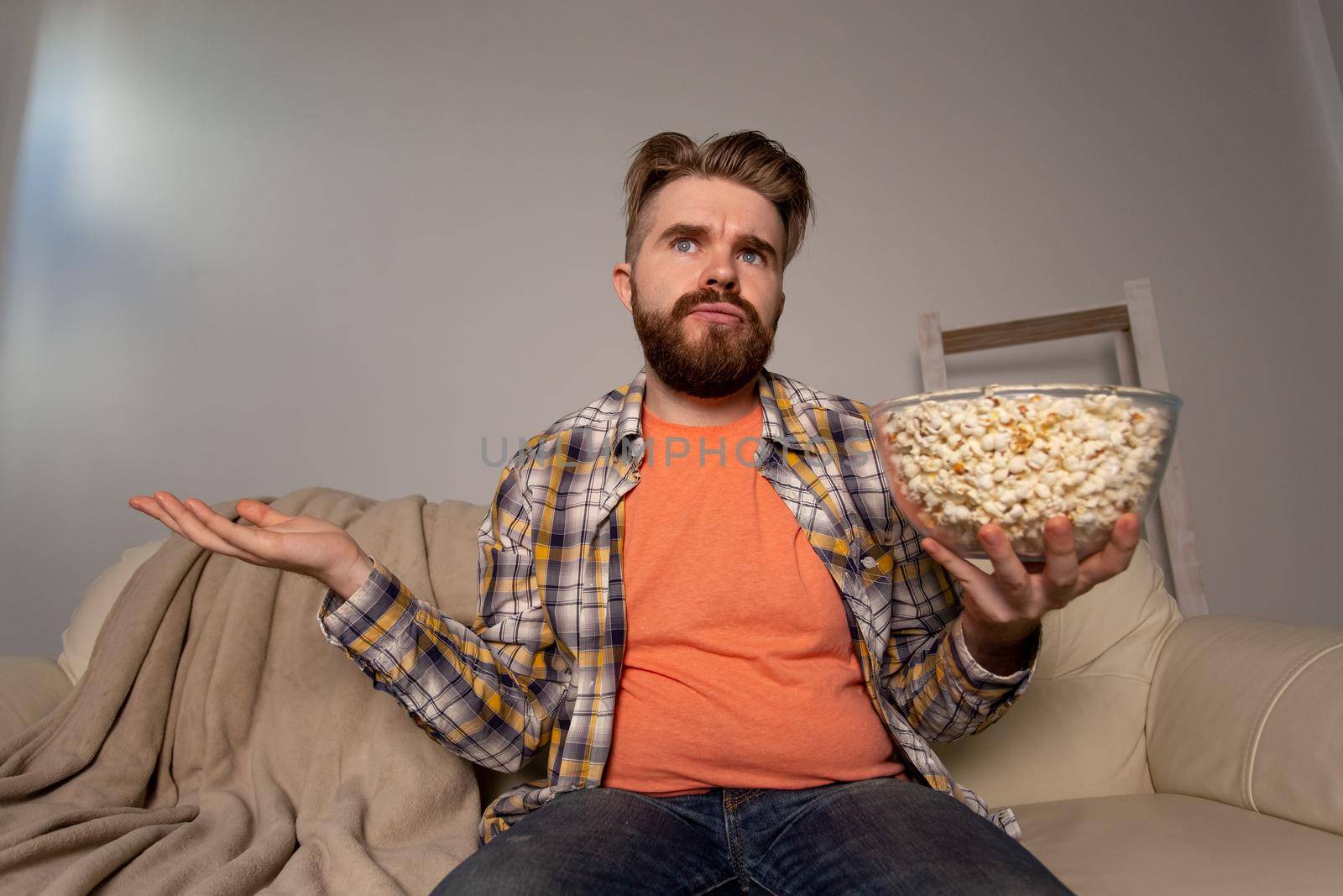 Bearded man watching film or sport games TV eating popcorn in house at night. Cinema, championship and fan.