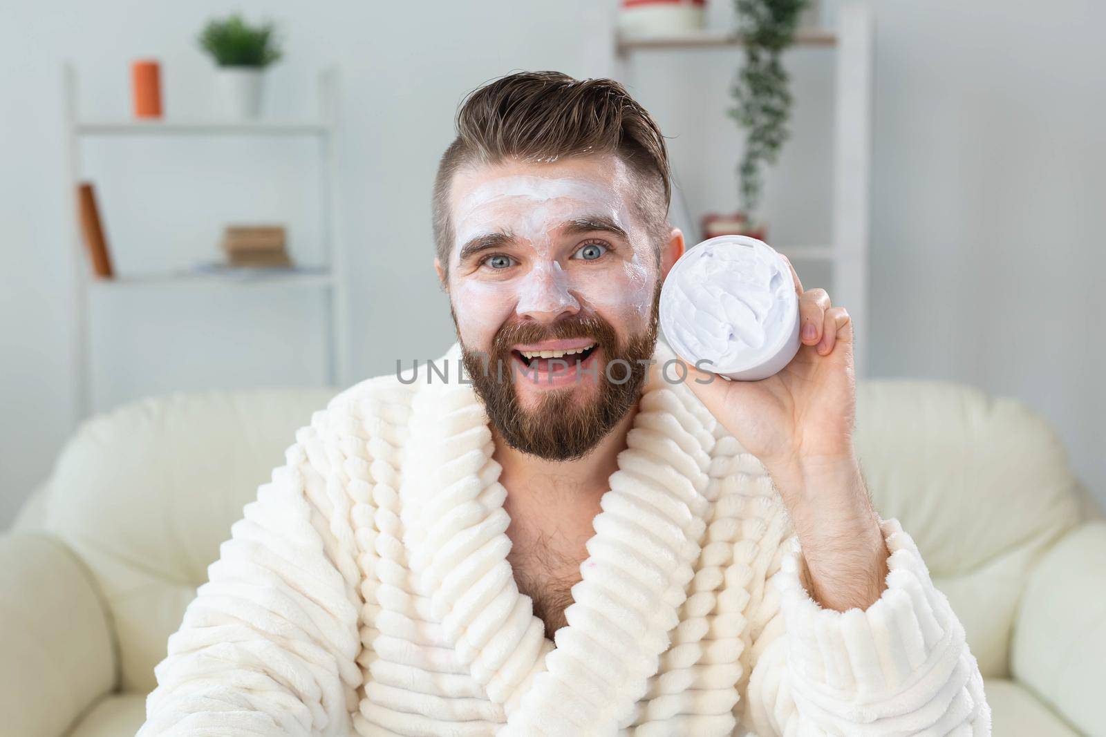 Closeup of handsome young man applying facial cream in front of mirror