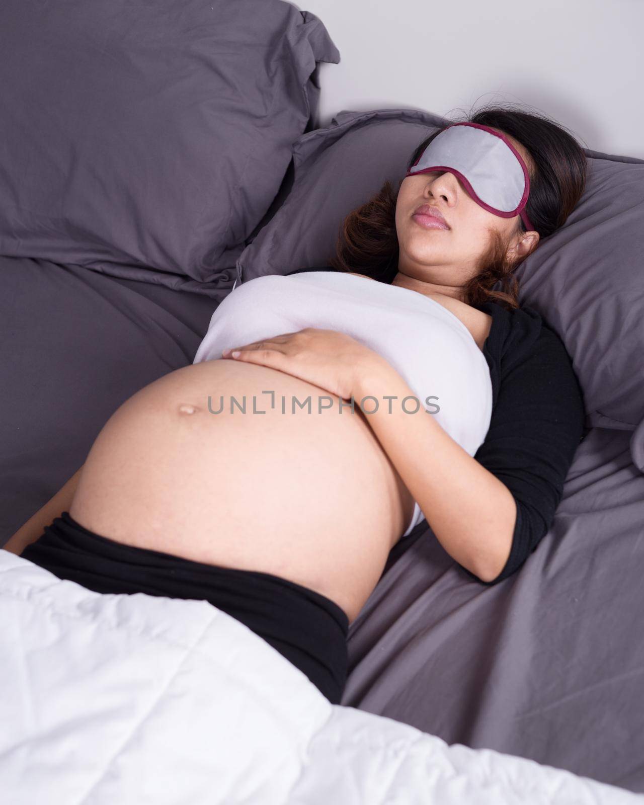 pregnant woman sleeping on bed in the bedroom by geargodz