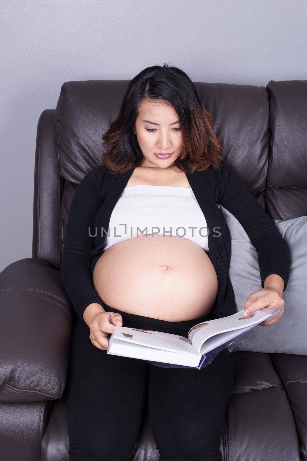 pregnant woman lying on sofa and reading book by geargodz