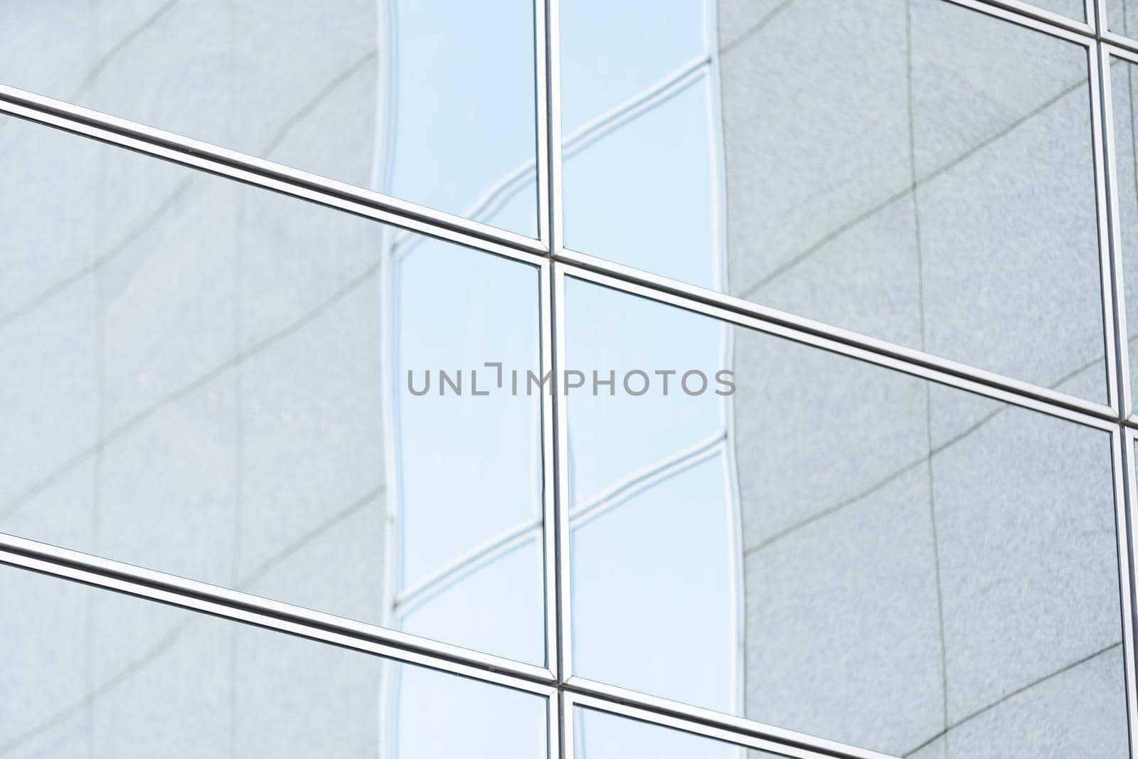 Perspective and underside angle view to textured background of modern glass building skyscrapers over blue cloudy sky.