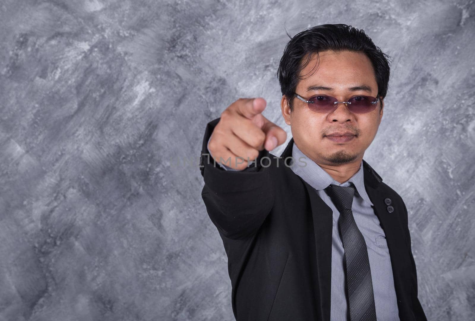 young business man pointing with wall backgroud