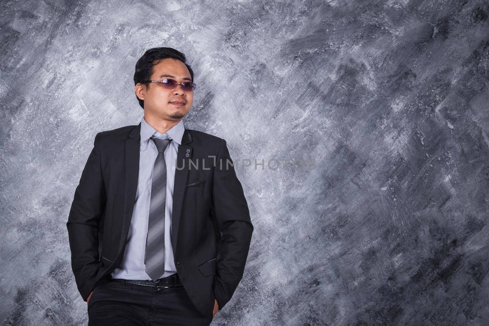 young businessman standing with hands in pockets  by geargodz