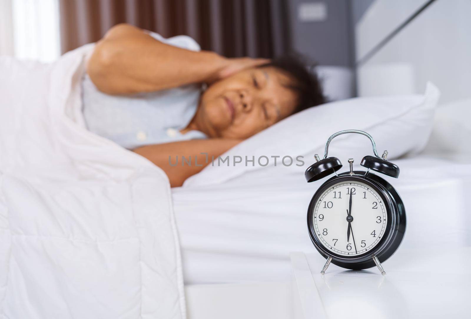 alarm clock wake up in the morning and senior woman close her ears 