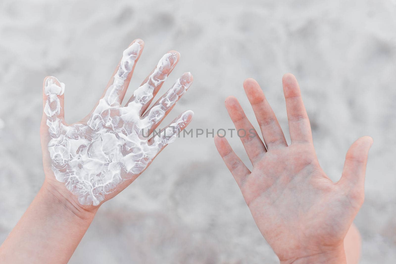 Hands of a young girl palms with sun cream and sun protection against the background of the beach by AYDO8