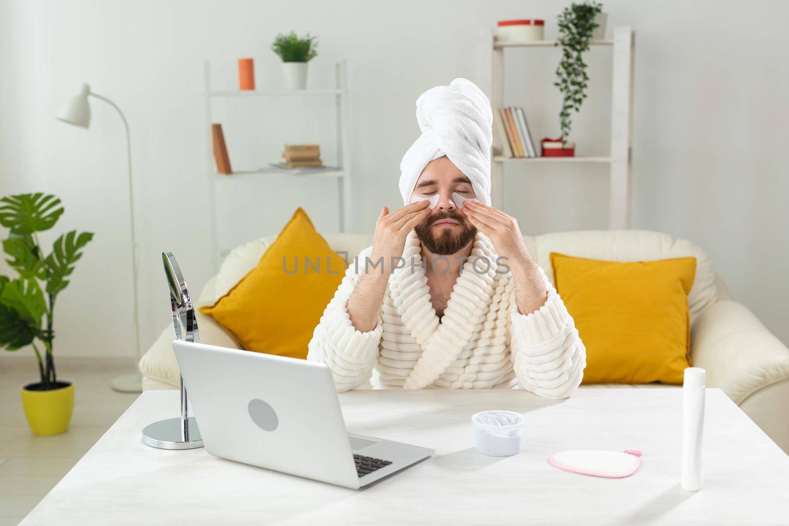 Bearded man applying eye patches on his face. Wrinkles and face home care for men