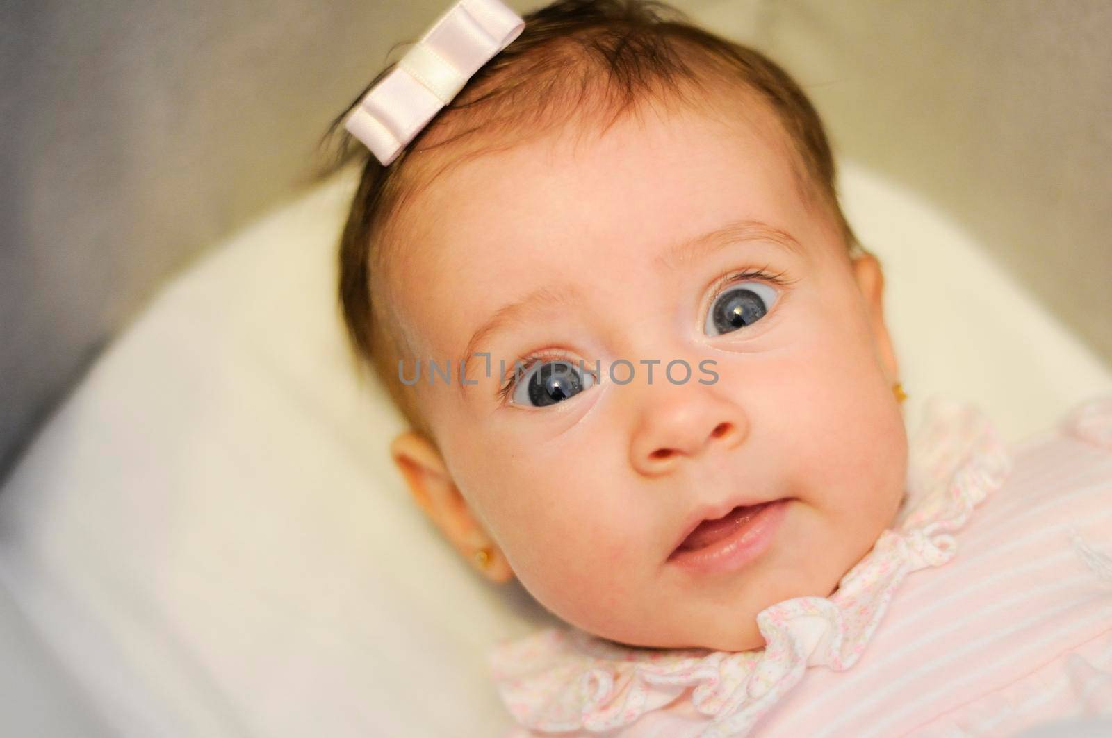 Little baby girl with funny surprise expression on her face. Two months old person.