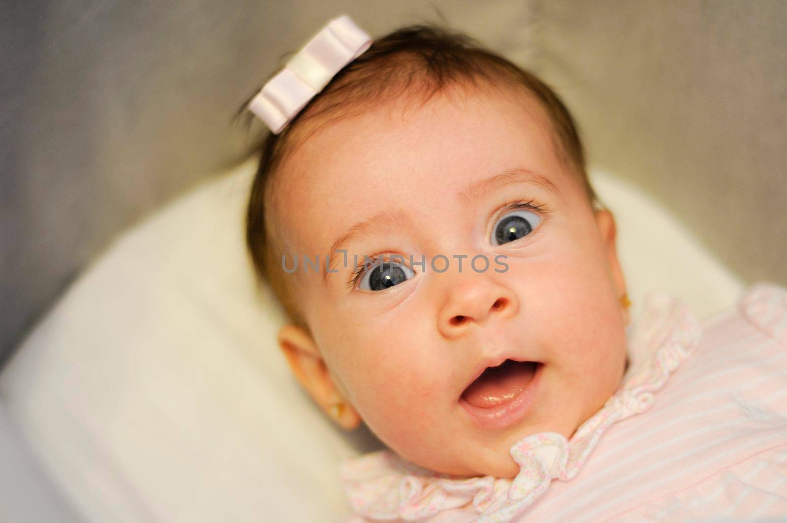 Little baby girl with funny surprise expression on her face. Two months old person.