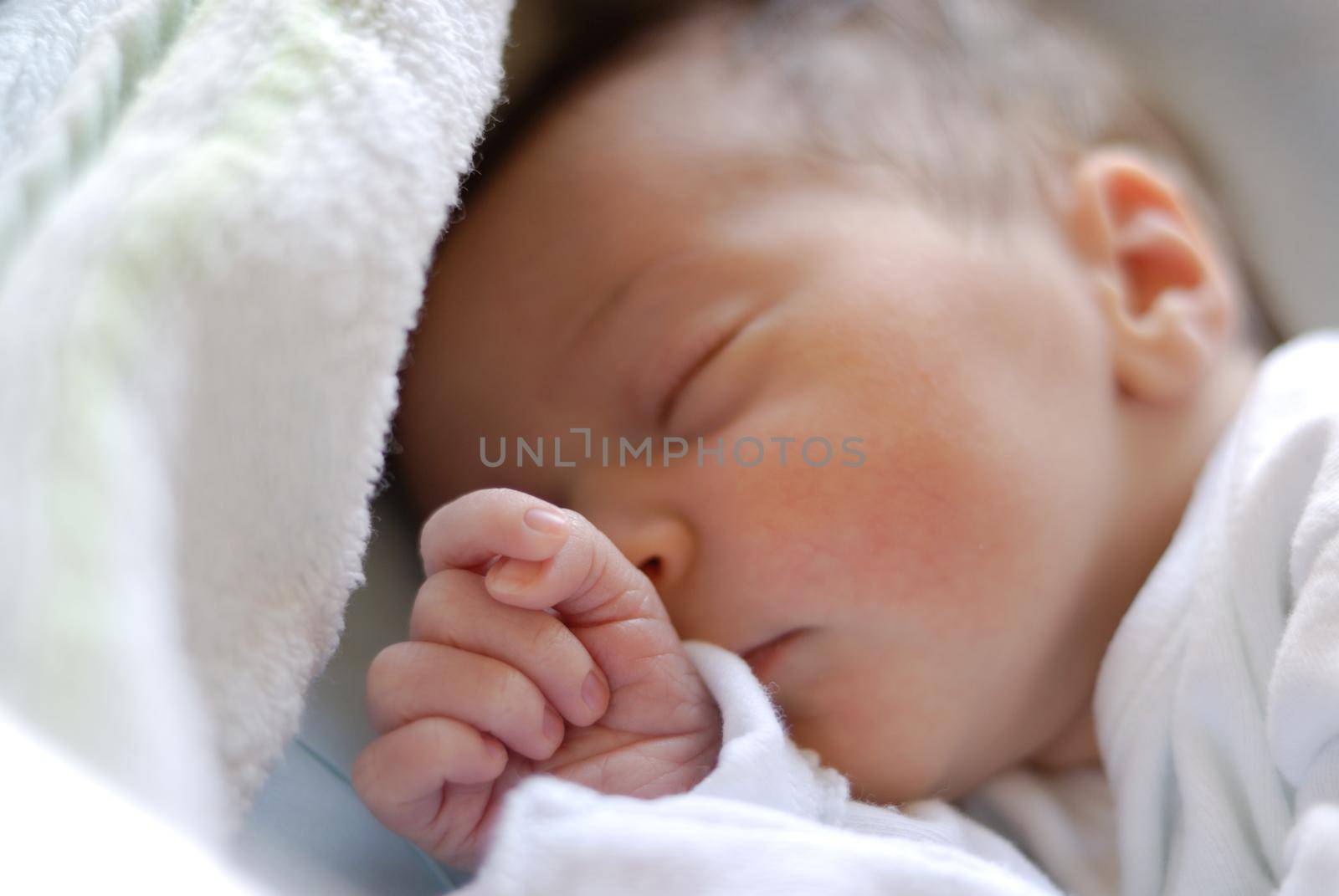 Newborn baby girl in hostpital bed sleeping. Caucasian female with adorable hand near her face.