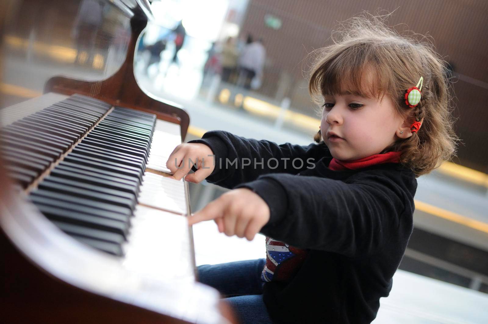 little girl having fun playing the piano by javiindy