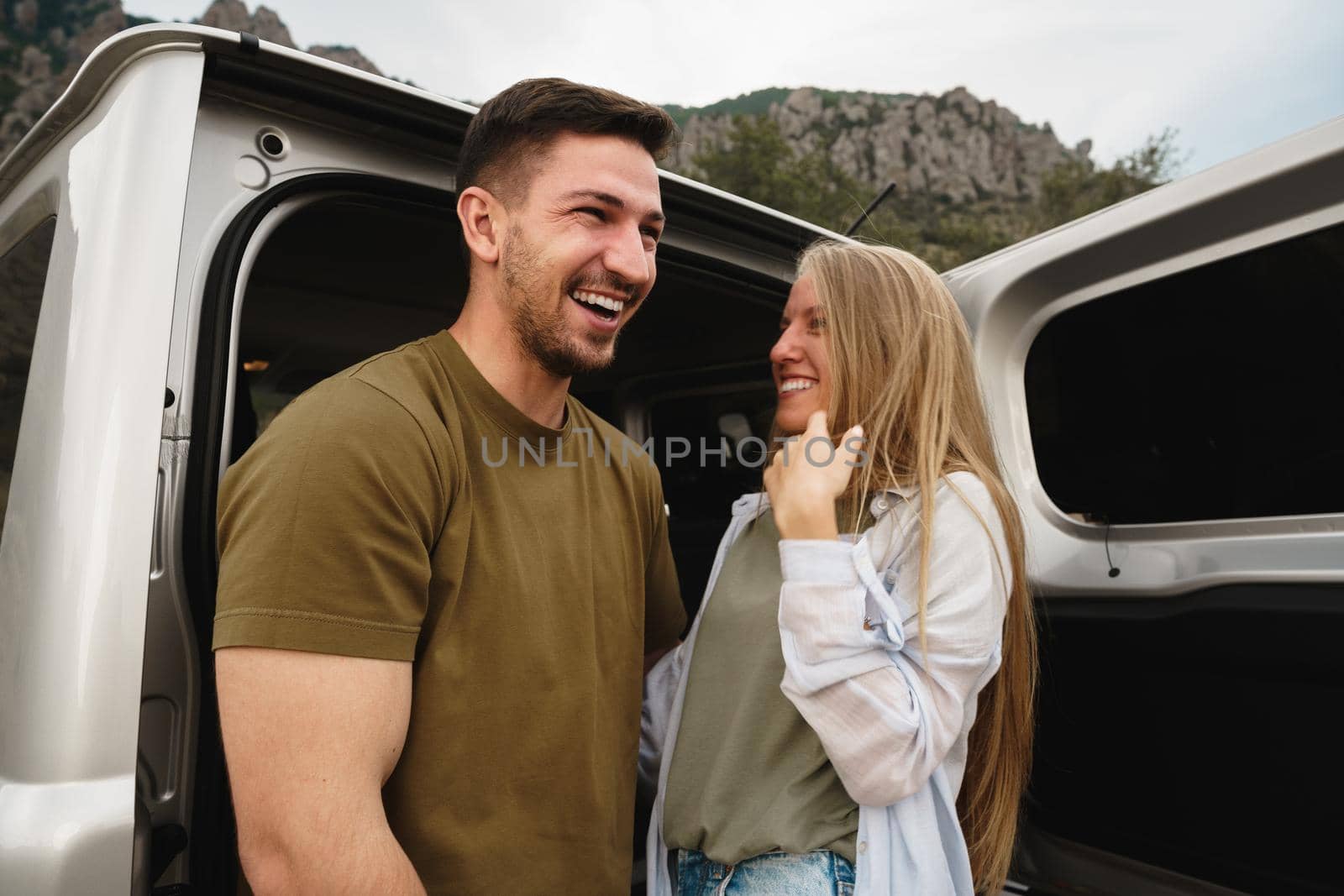 Young happy couple on a road trip sitting in car trunk outdoor