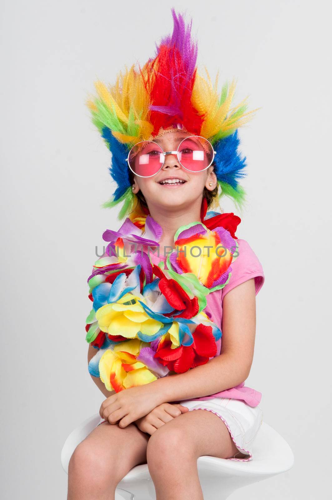 Funny beautiful party little girl in disguise with wig in many colors and pink round sunglasses