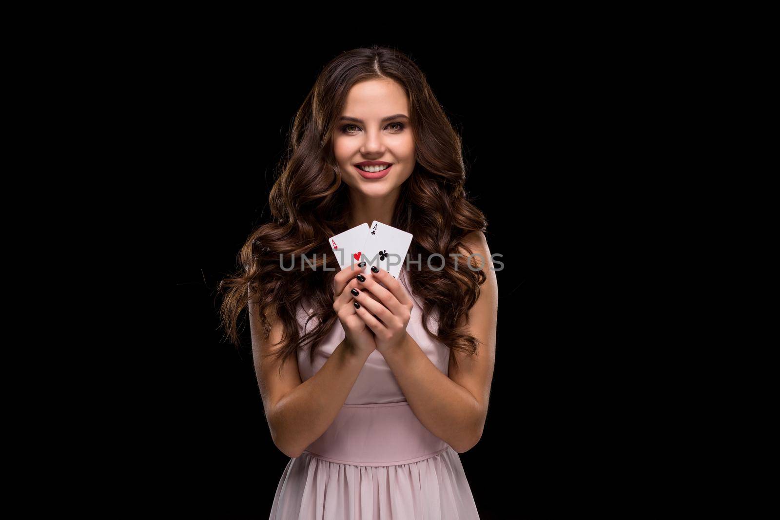 Attractive young woman in a sexy light dress holding the winning combination of poker cards. Two Aces. Studio shot on a black background. Casino