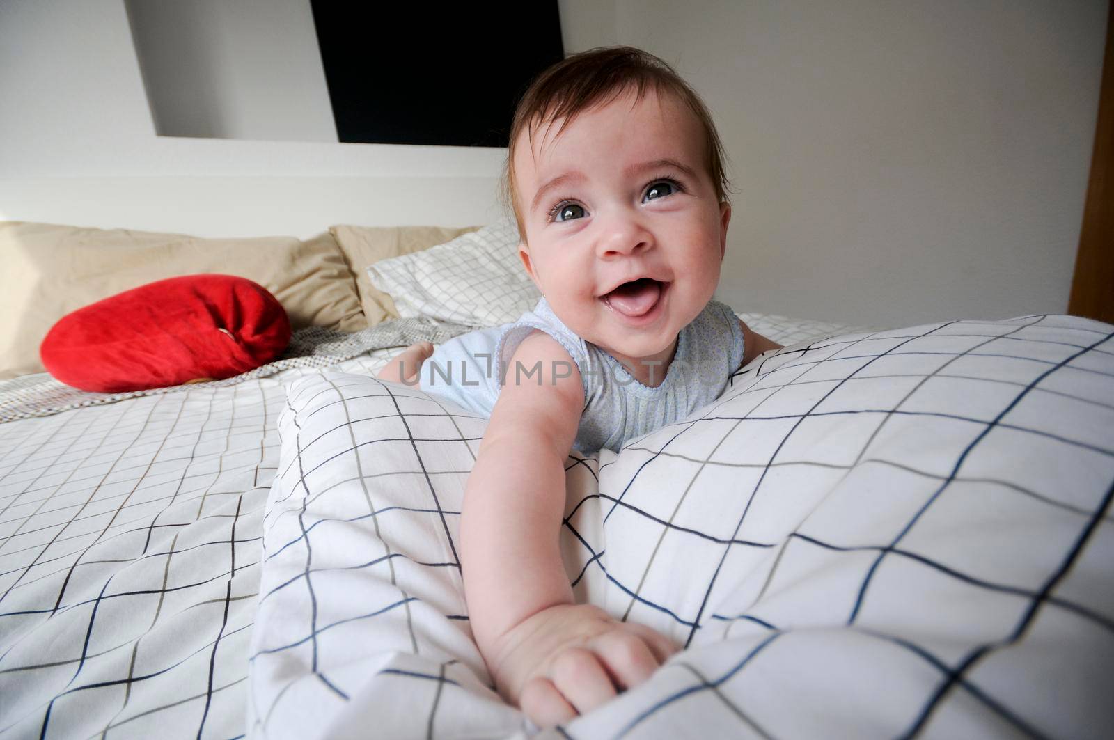 Baby girl lying on her parents bed with funny expression by javiindy