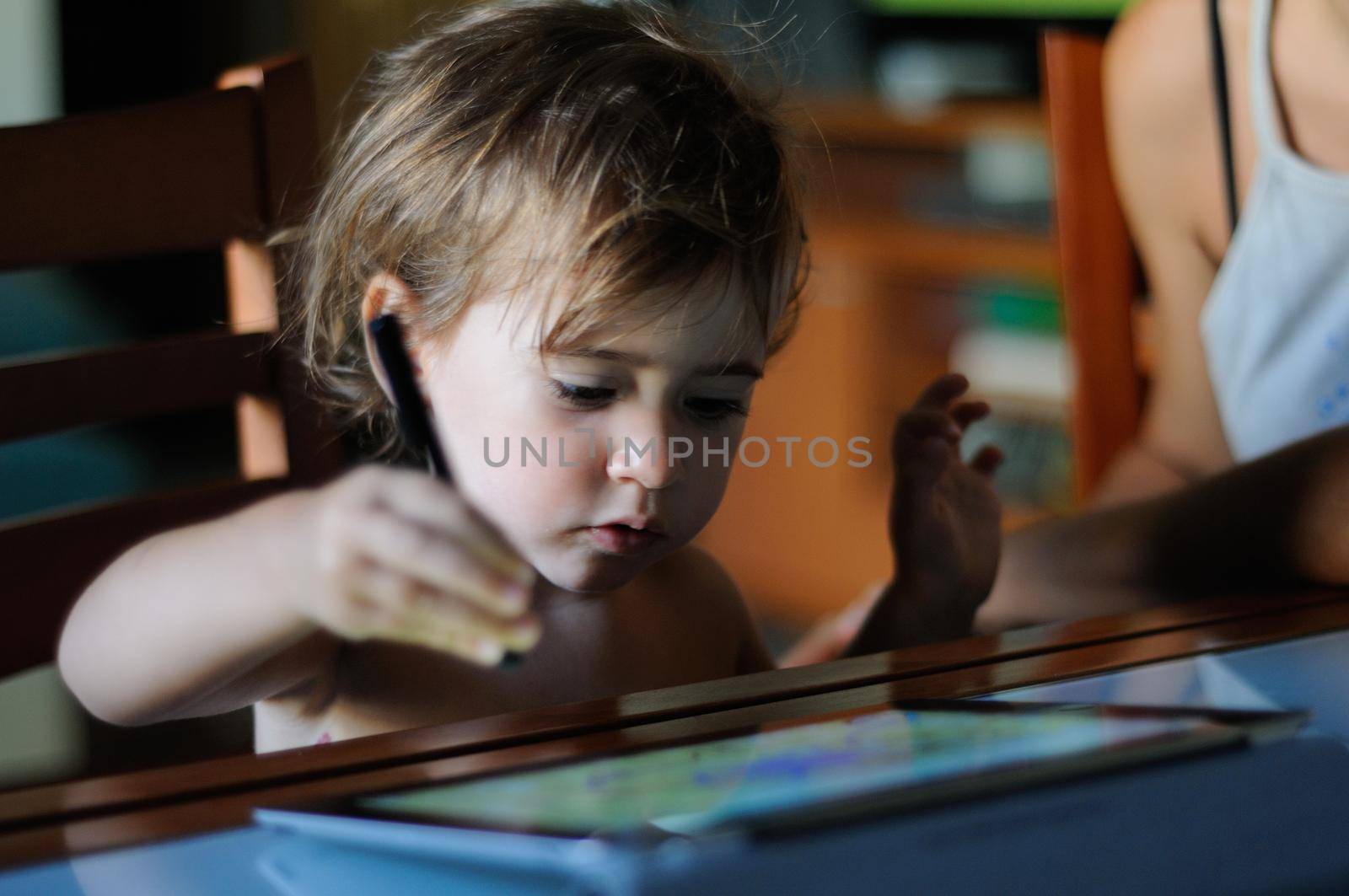 Little girl, two years old, painting with a digital tablet at home.