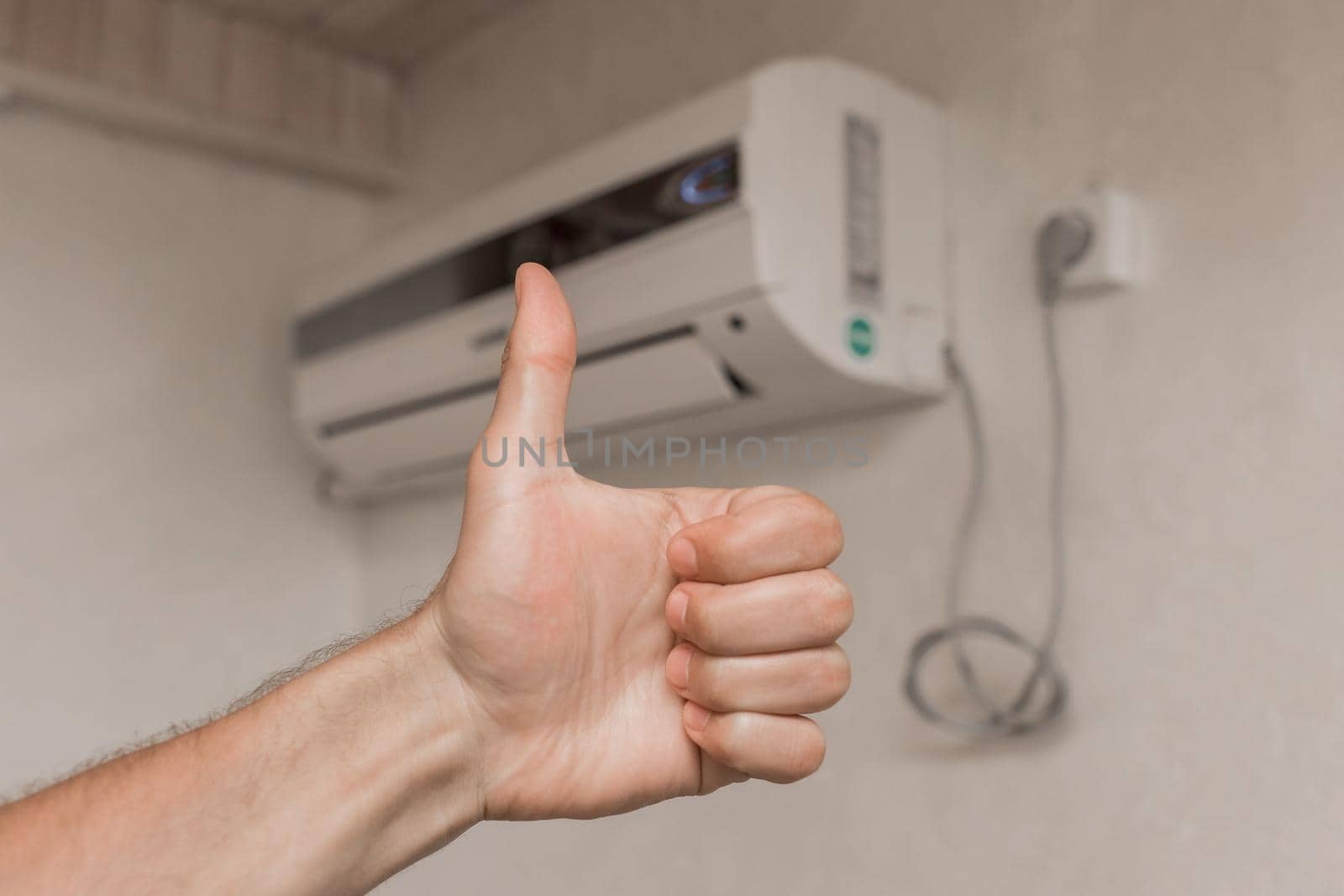The guy's hand shows the class thumbs up against the background of the air conditioner on the wall in the room background by AYDO8