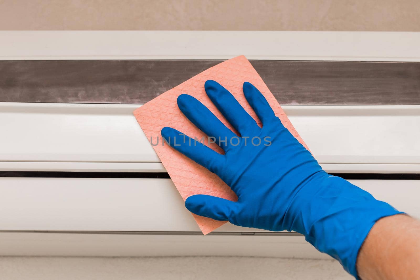 The hand of a man in a blue rubber household glove wipes and cleans the air conditioner. Maintenance and cleaning indoor service by AYDO8