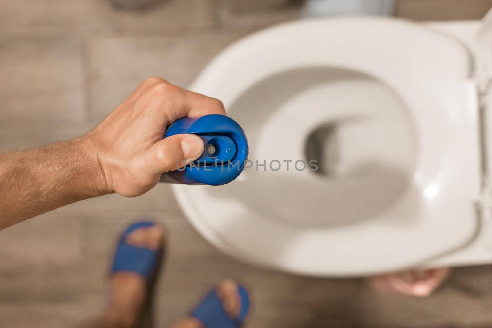 The guy's hand holds and sprays the air freshener in the toilet or bathroom. Home Hygiene Concept.