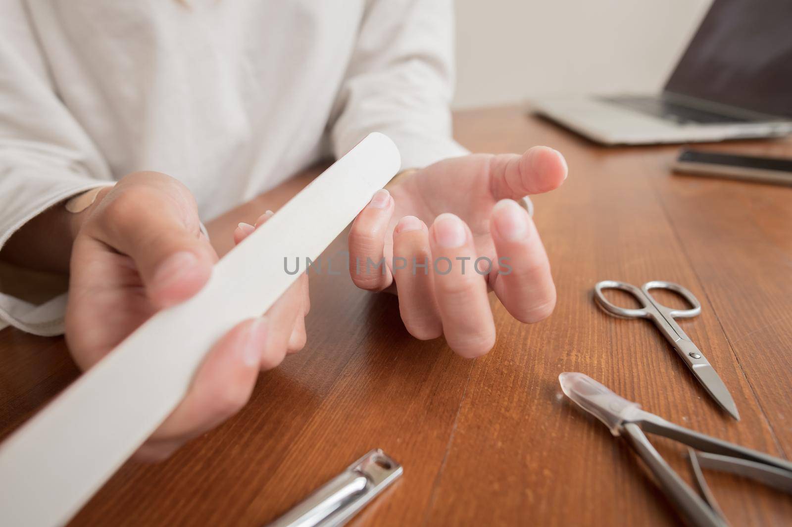 Caucasian girl makes herself a manicure at home. Close-up young woman uses nail clippers by yanik88