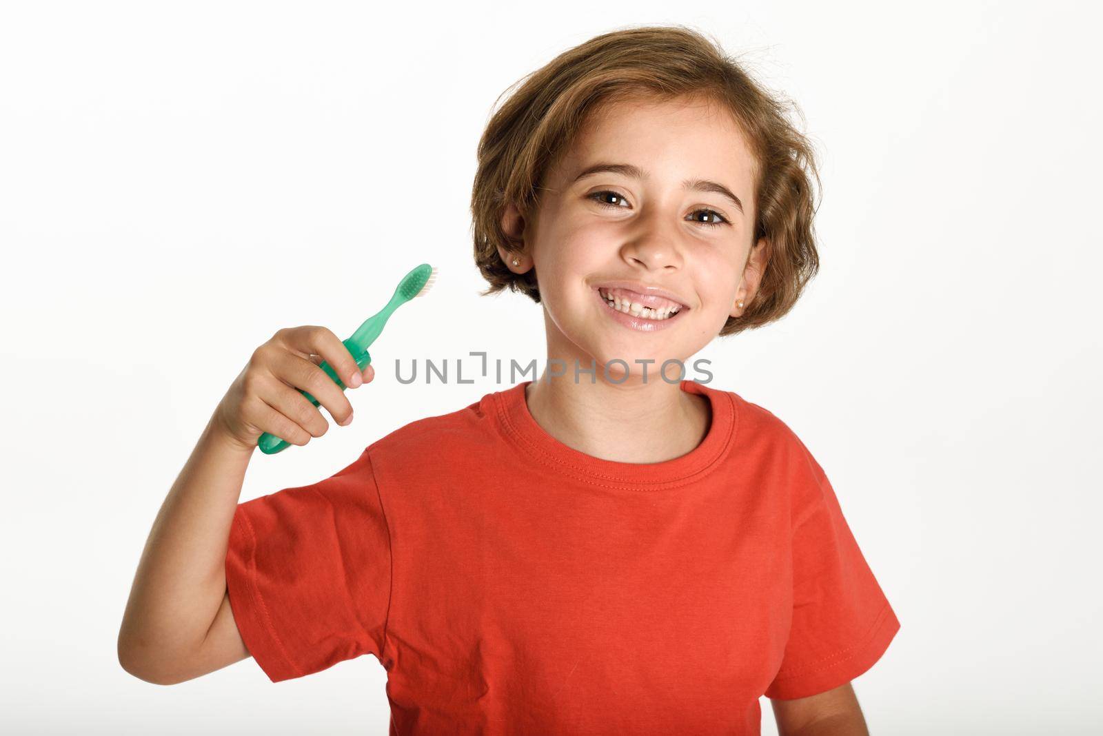 Happy little girl brushing her teeth with a toothbrush isolated on white background. Studio shot.