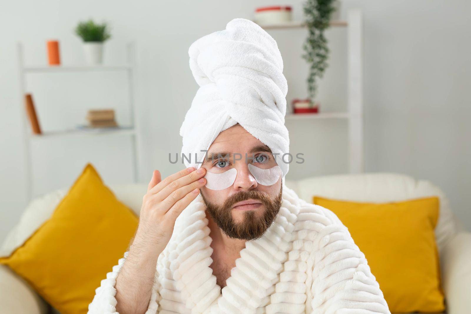 Young man with patches under the eyes at home. Concept of cosmetology for men.Spa at home, body and skin care.