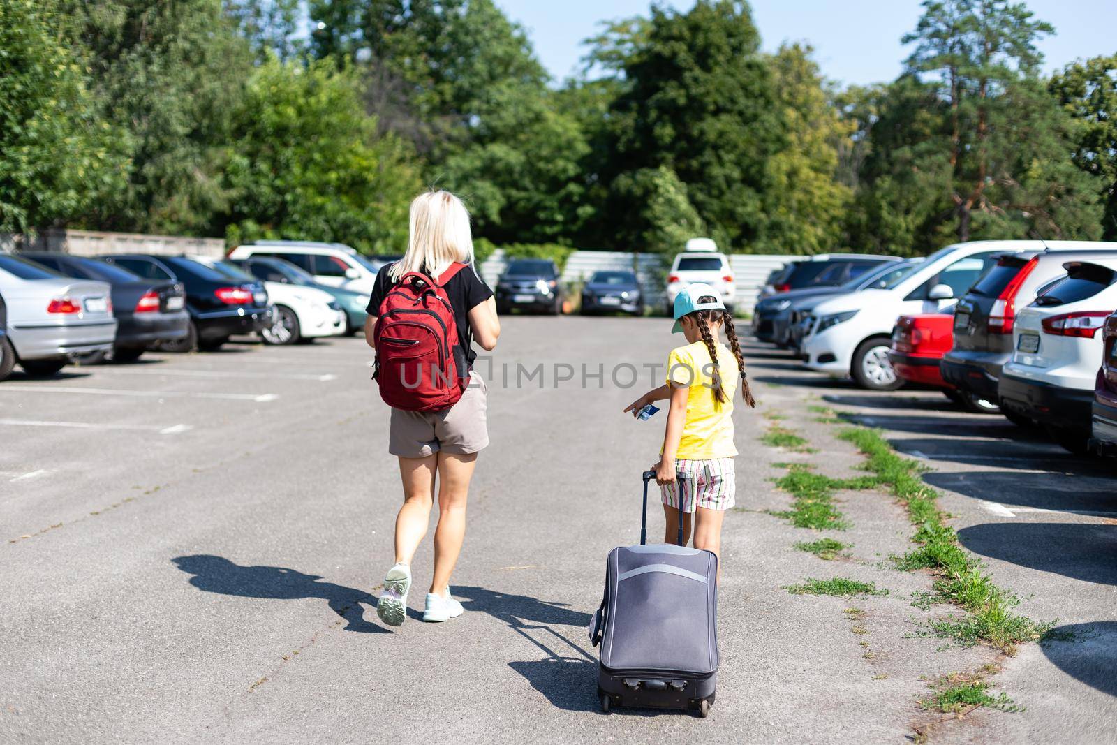 mother and daughter with suitcase in the parking lot.