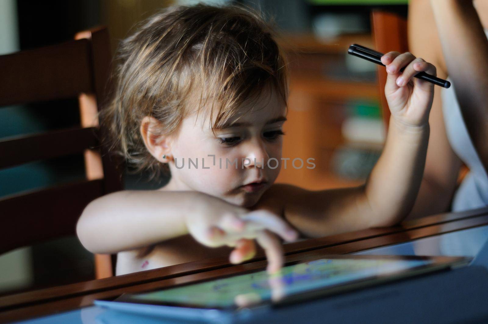 Little girl, two years old, painting with a digital tablet at home.