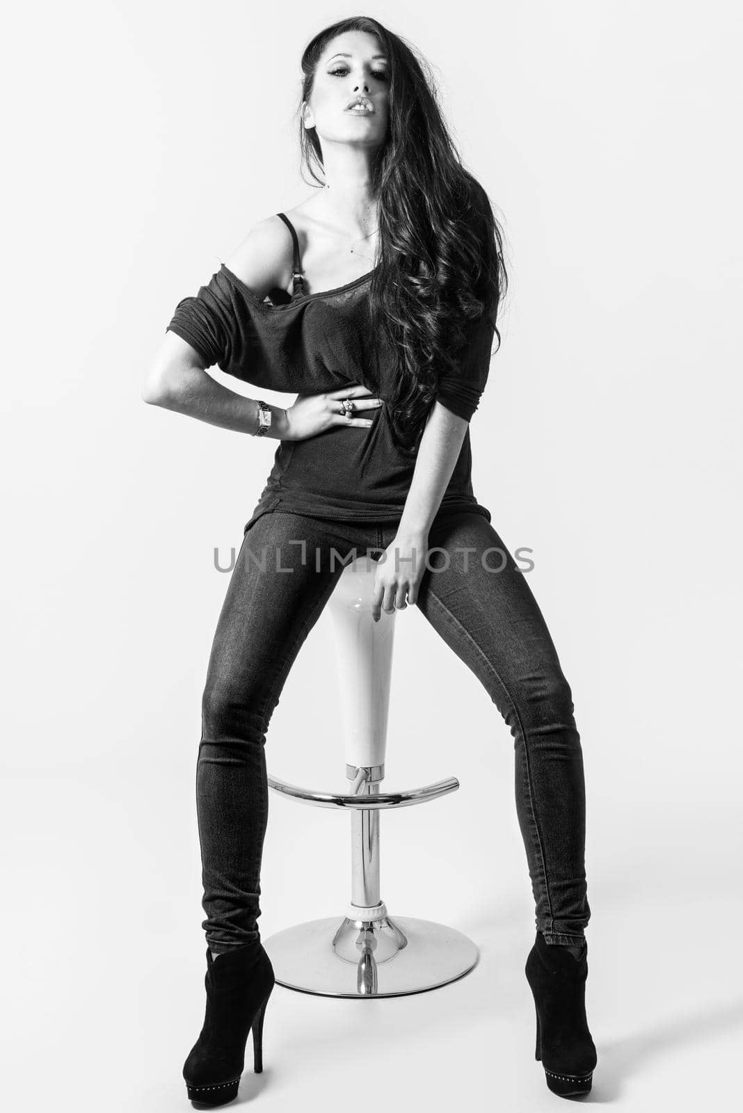 Brunette woman with blue eyes wearing sweater and blue jeans on white background. Studio shoot