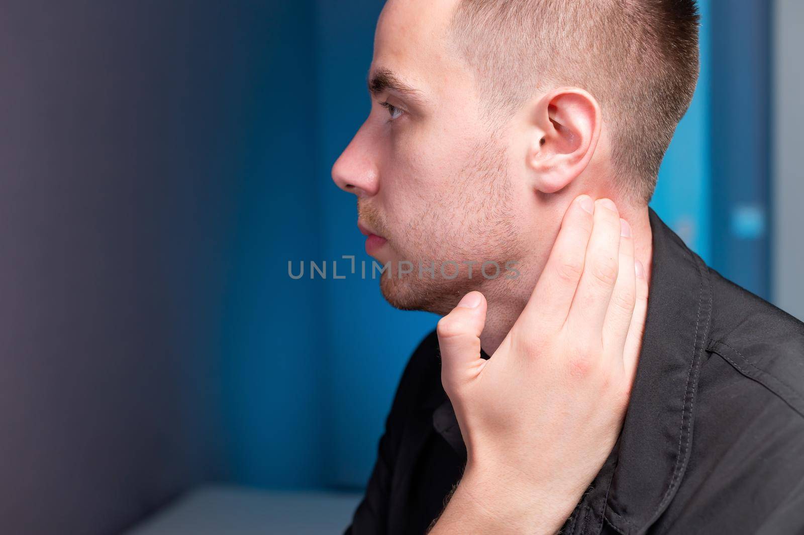 Close-up of a man holding his neck with his hand. Neck pain and self-massage.