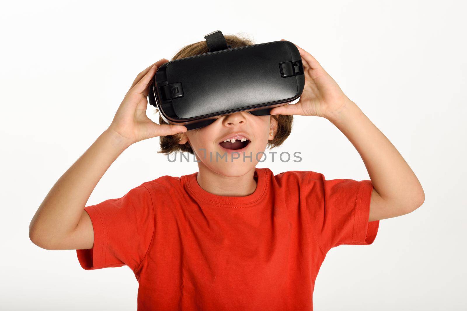 Little girl looking in VR glasses and gesturing with his hands. Cheerful surprised child wearing virtual reality goggles watching movies or playing video games, isolated on white background.