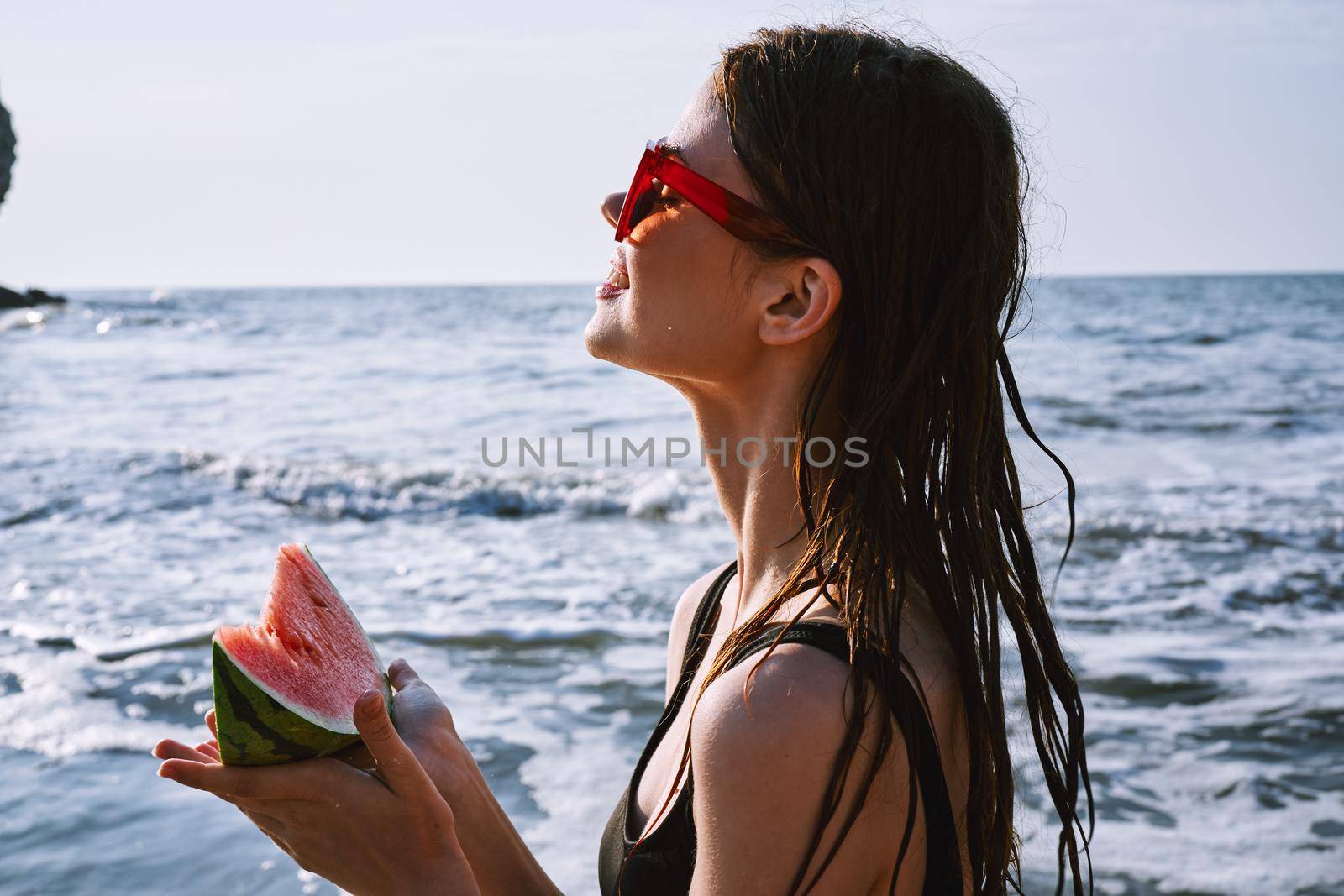 pretty woman in a black swimsuit with a watermelon in her hands summer Ocean. High quality photo