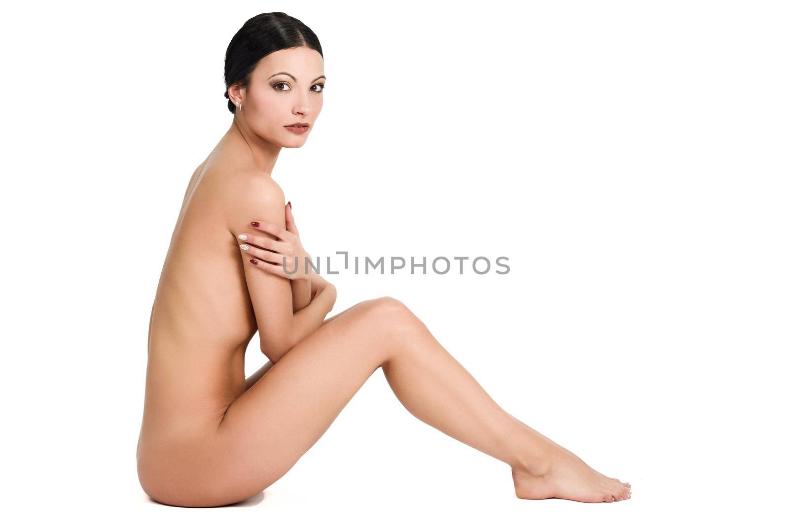 Young naked brunette woman sitting on white background. Perfect epilated skin