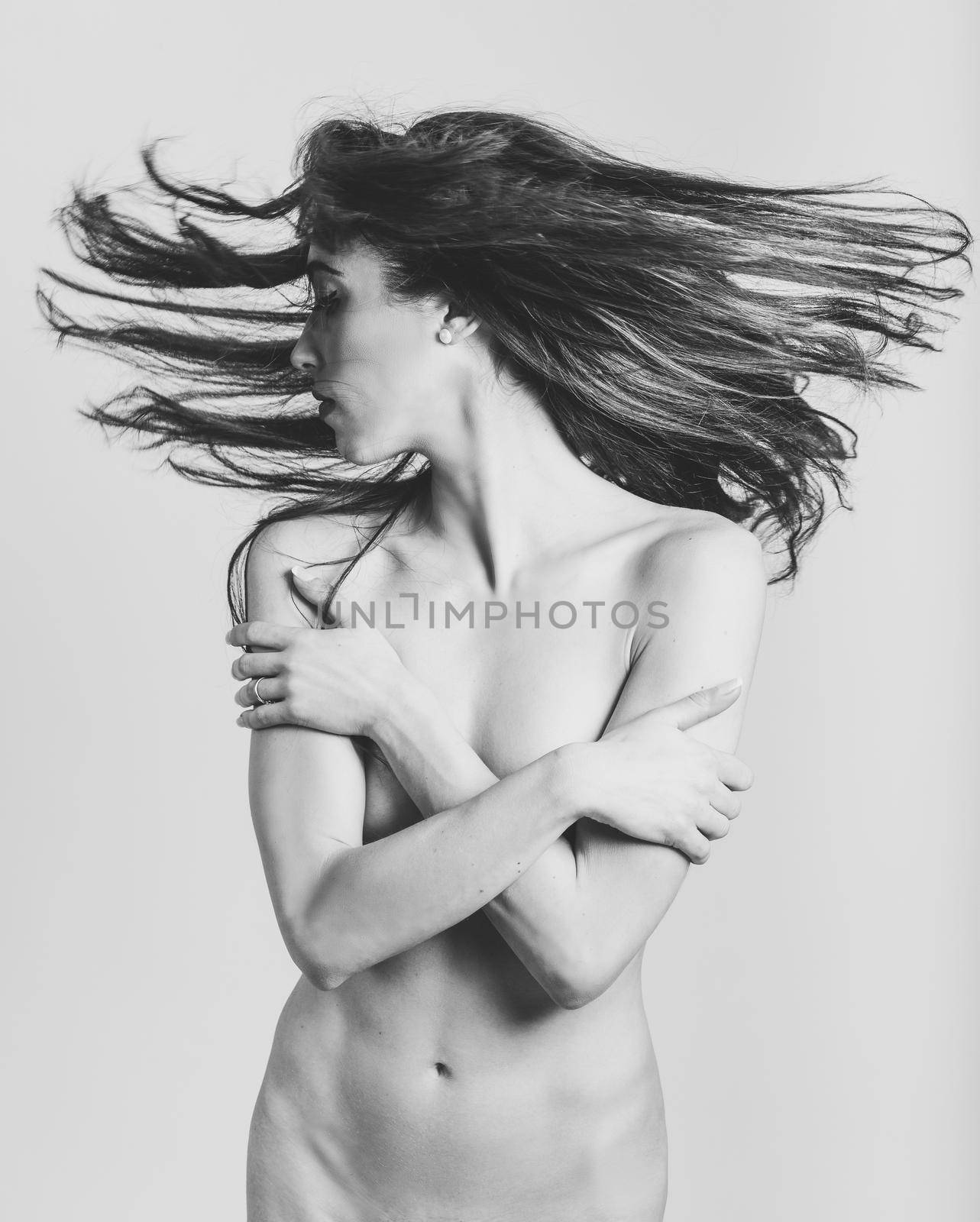 Beautiful nude woman with moving hair on white background.