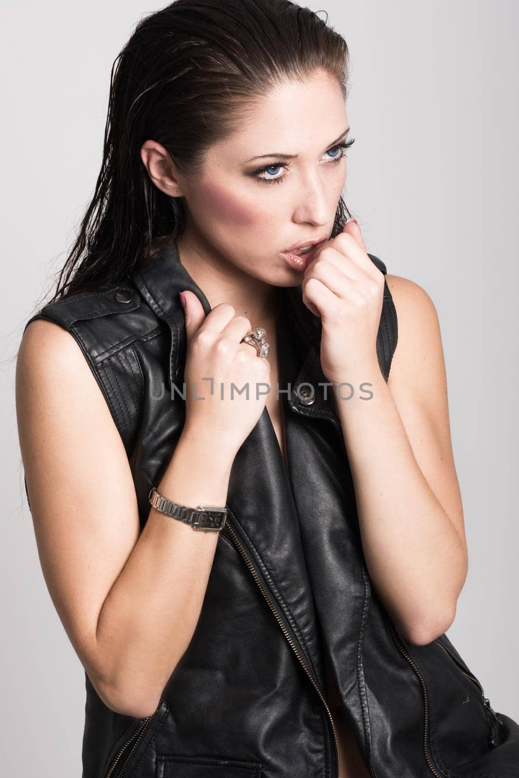 Brunette woman with blue eyes wearing black leather jacket and panties on white background. Studio shoot