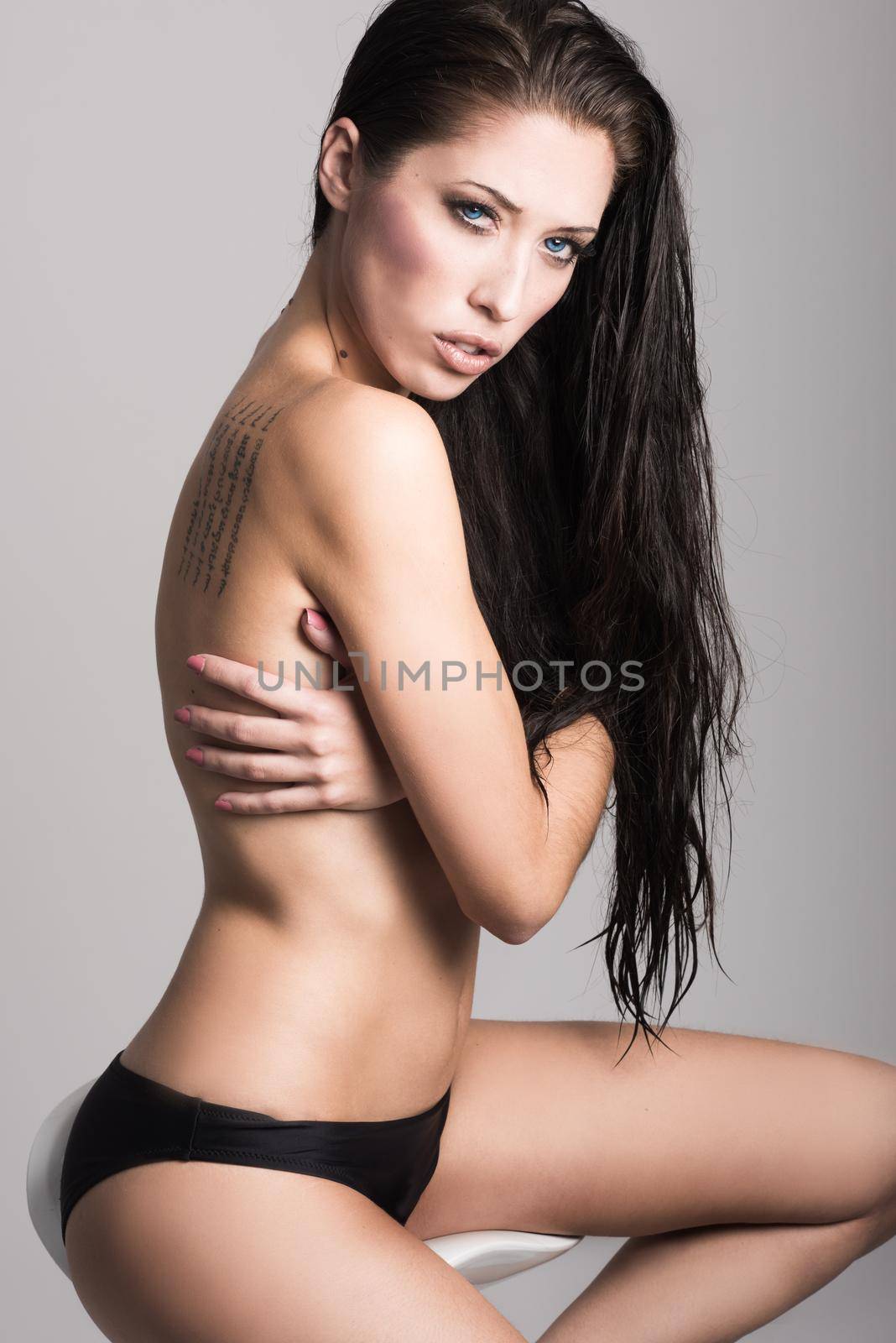 Half naked brunette woman wearing panties with very long curly hair on white background. Studio shot