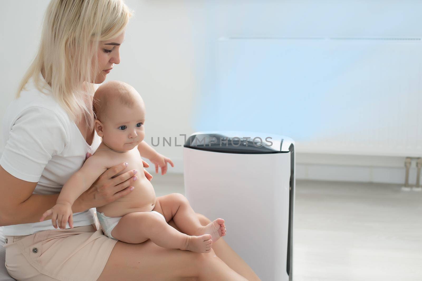 mother and baby near air purifier at home by Andelov13