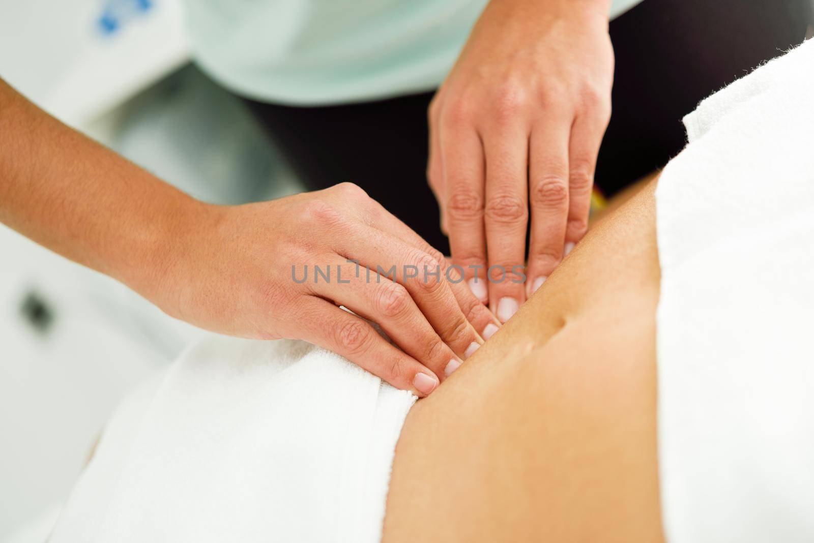 Hands massaging female abdomen.Therapist applying pressure on belly. Woman receiving massage at spa salon