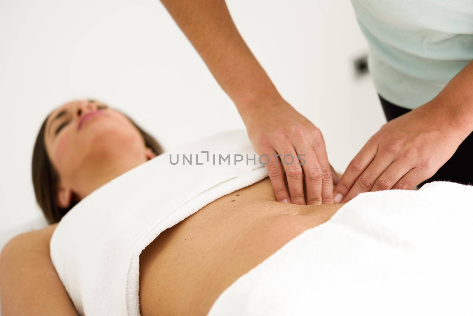 Hands massaging female abdomen.Therapist applying pressure on belly. Woman receiving massage at spa salon